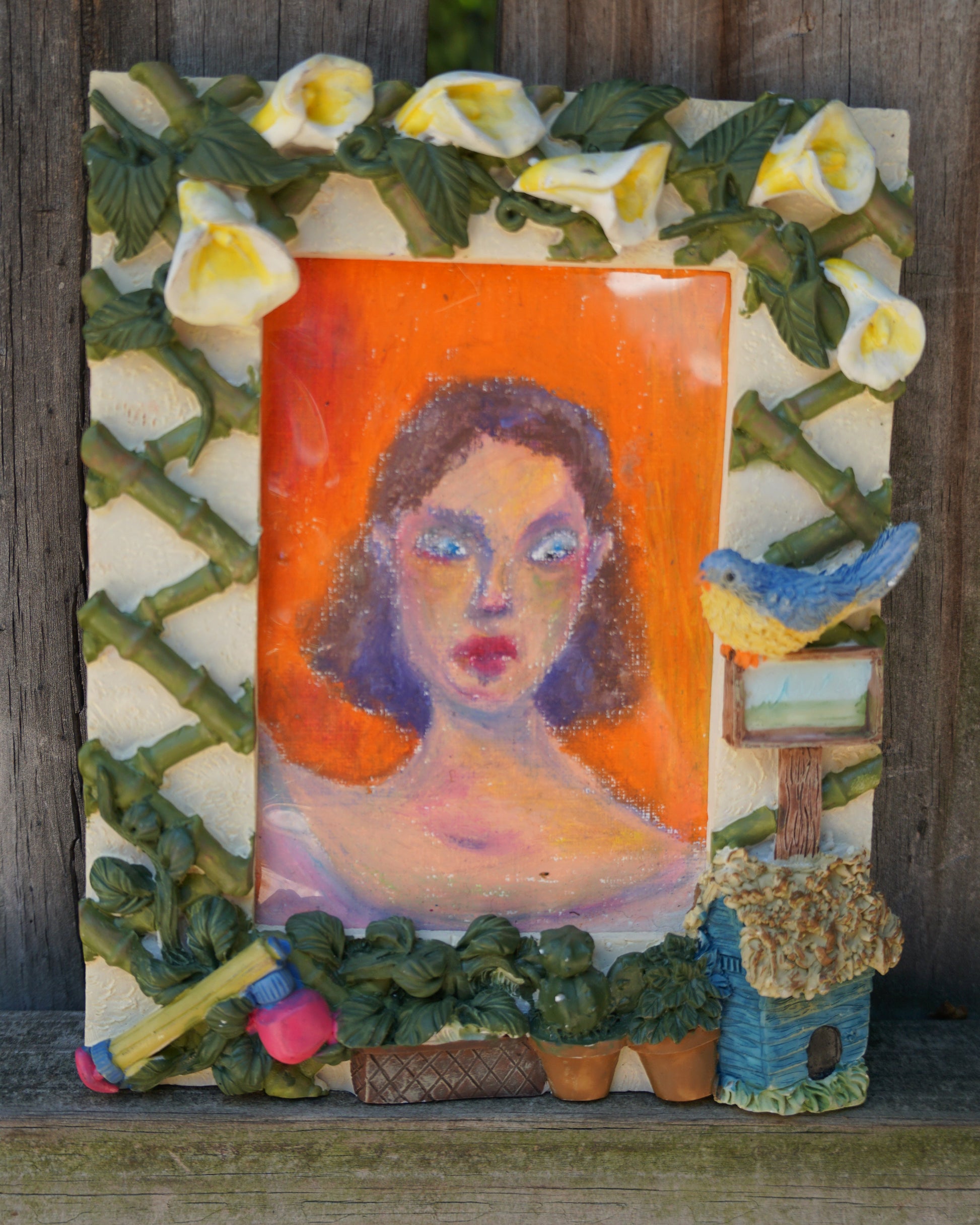 Decorative wall art with a portrait of a woman, flowers, and a bird on an orange background.