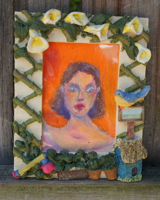 Decorative wall art with a portrait of a woman, flowers, and a bird on an orange background.